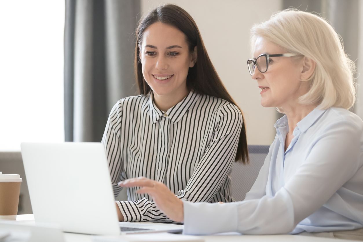 Confident experienced female employees share information with young worker stock photo