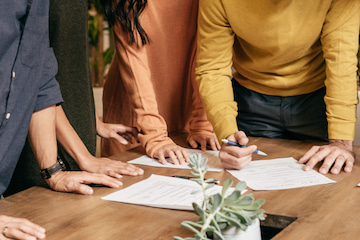 businesspeople signing paperwork at desk