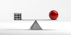A balance with one side having a red ball and the other having several smaller silver balls