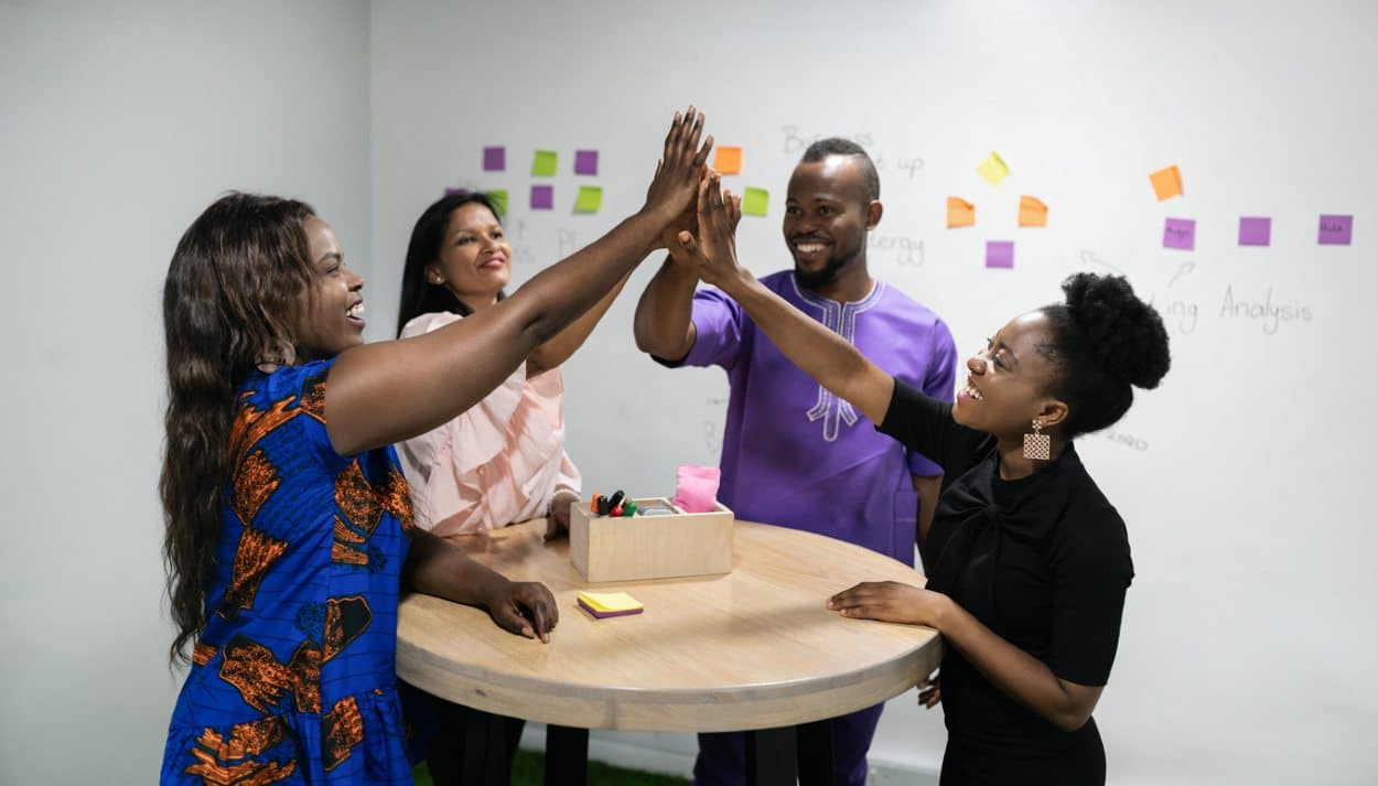 coworkers high fiving each other around a table