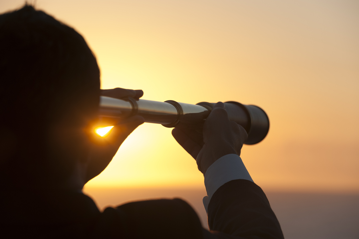 Businessman looking to the future with telescope