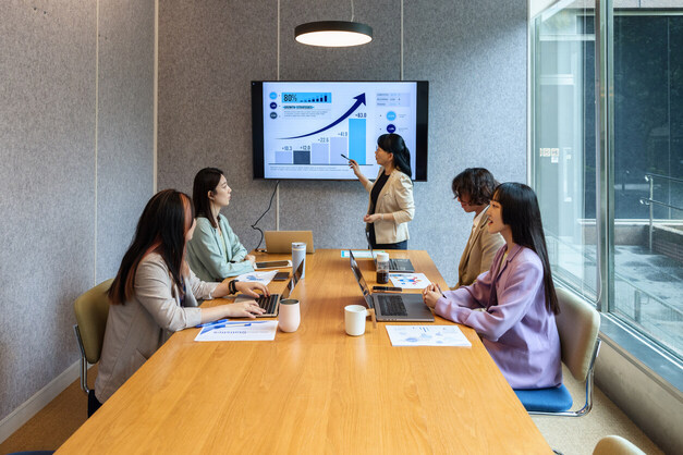 business graph on screen as employees look on