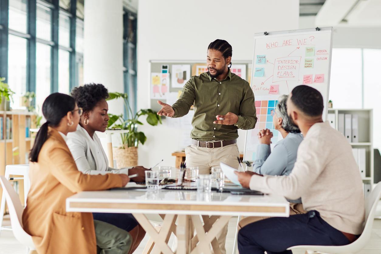 team leader standing at head of table with team sitting around table