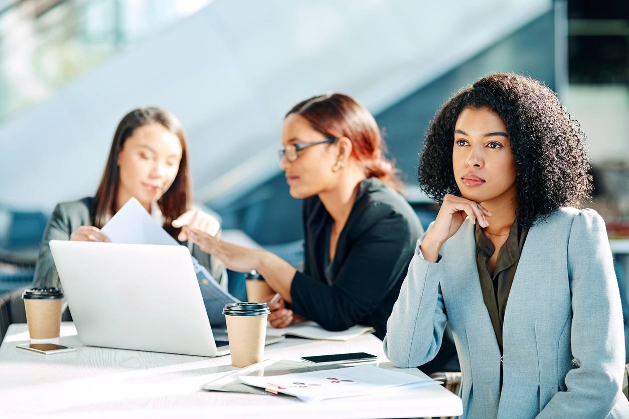 employee looking off in the distance while 2 coworkers talk behind her