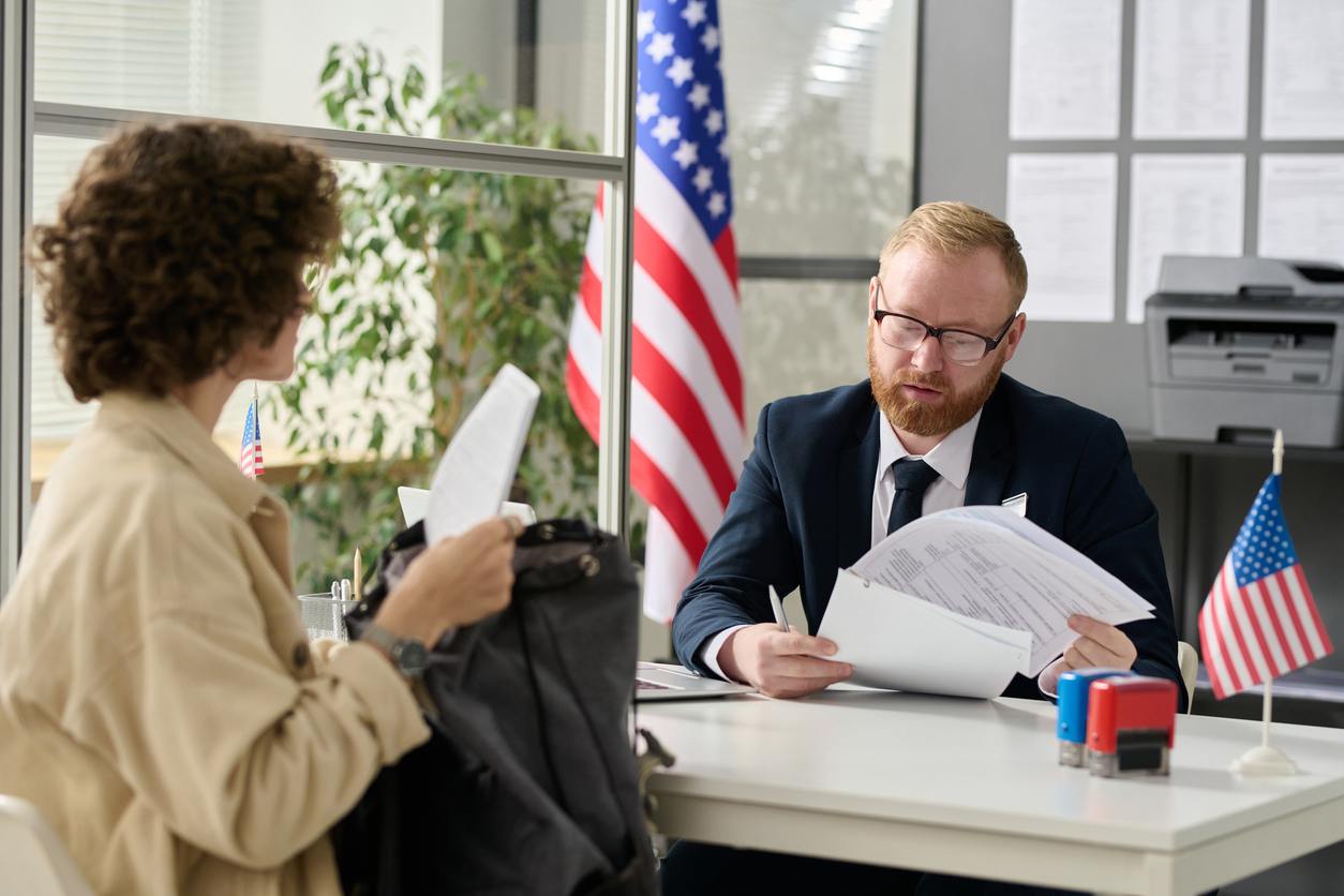 employees discussing paperwork with American flag in background