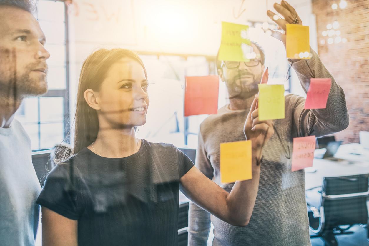 team gathered around a glass wall with sticky notes