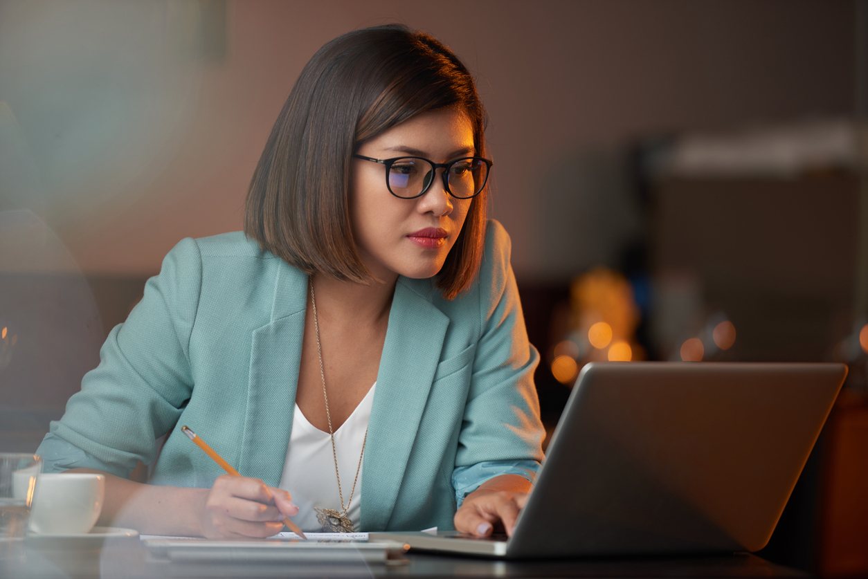 business woman working on laptop and taking notes