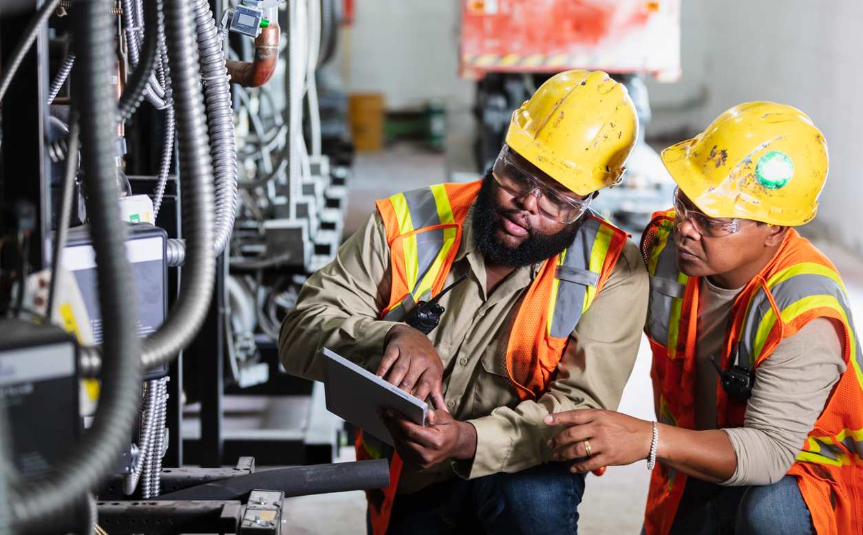 workers in a manufacturing plant looking at clipboard