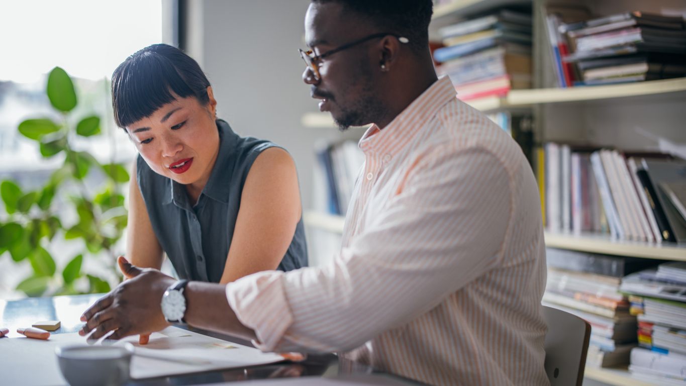 two employees sitting at a table coaching concept