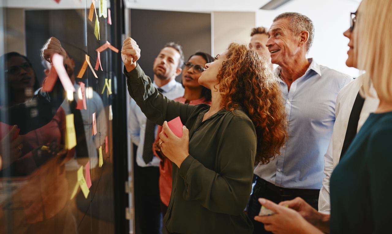 team looking at sticky notes attached to a glass wall