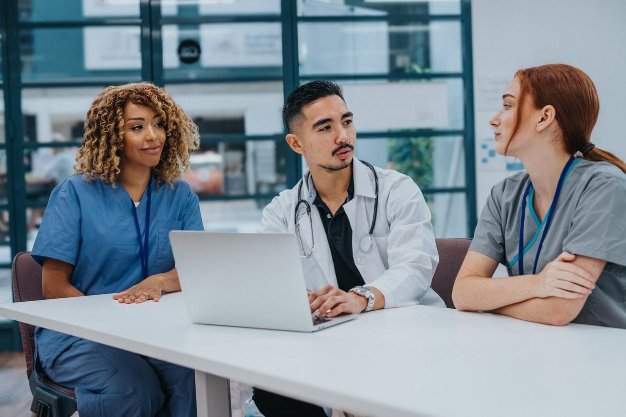 frontline healthcare workers sitting at table with laptop