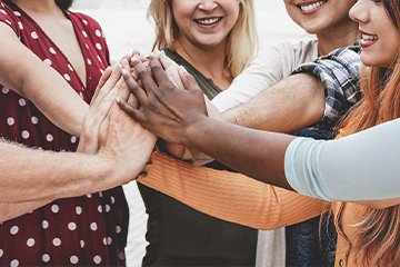 diverse group of hands held together with smiling individuals