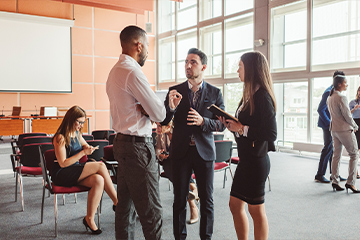 businesspeople standing in group discussion in large office space