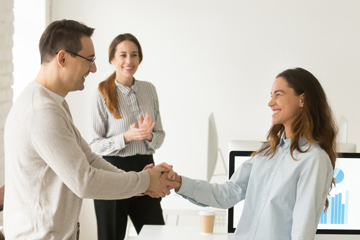 smiling woman shaking hands with smiling man in group setting