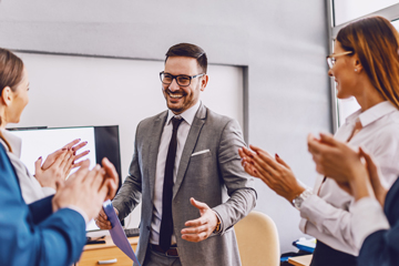smiling businesspeople standing and clapping after presenter finishes his presentation