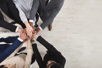 top view looking down at businesspeople with hands all together in a huddle