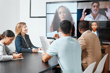 employees in conference room during video call with multiple virtual participants