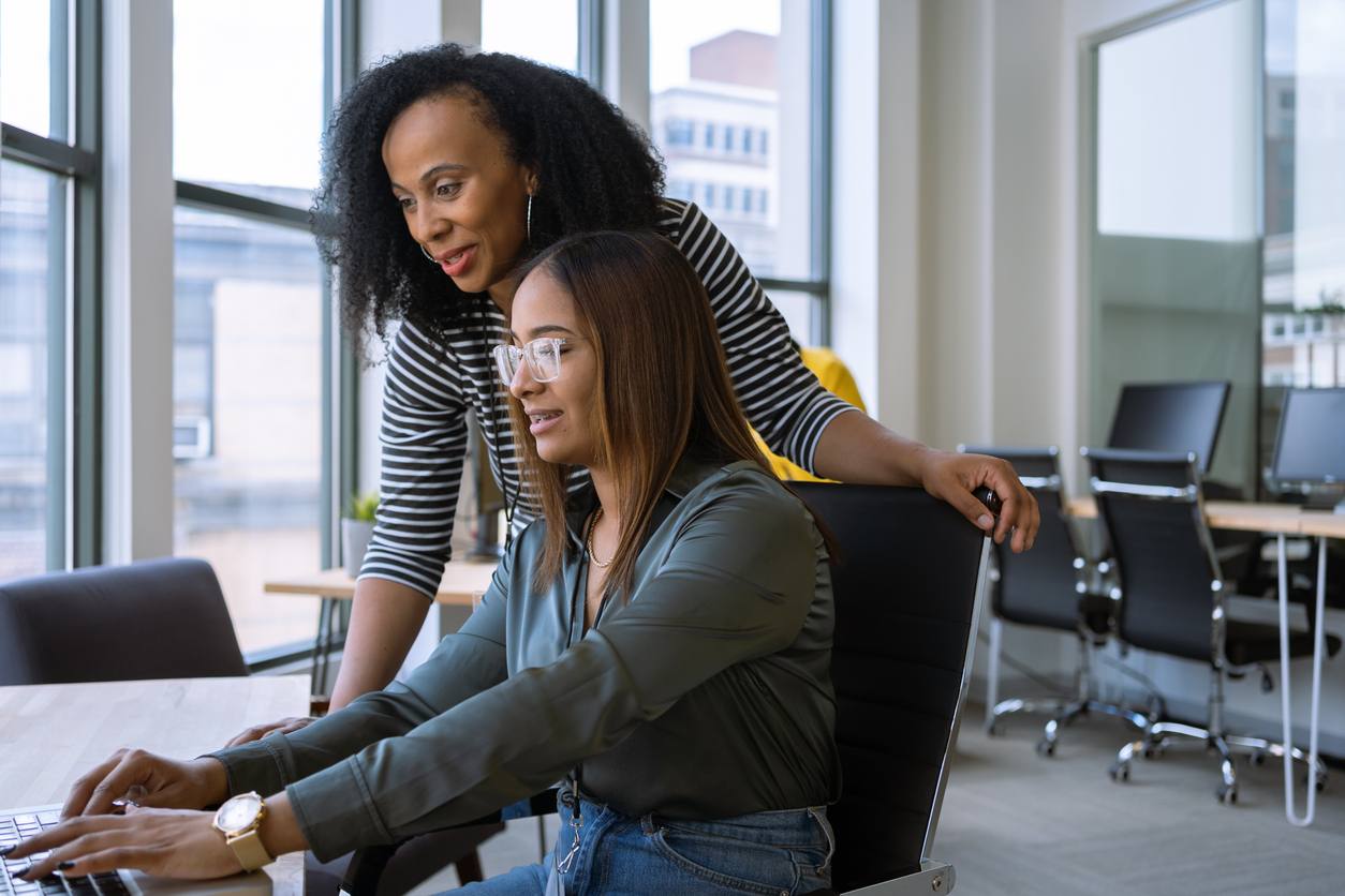 two female coworkers working on a laptop in an office