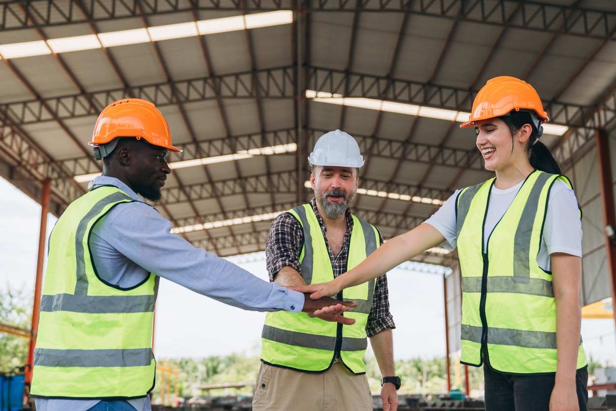 blue collar employees placing hands in middle to cheers