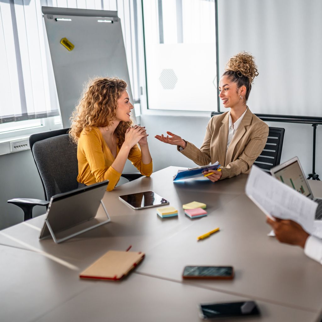 two female coworkers talking at a table